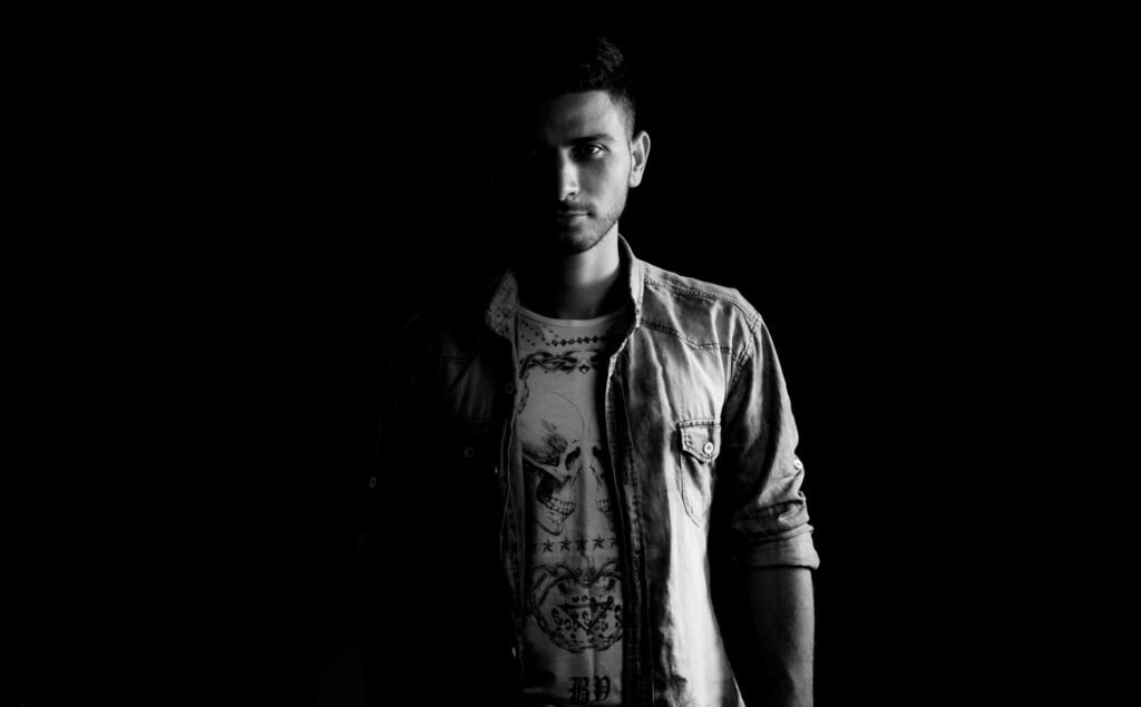 Black and white portrait of a man in a denim jacket captured dramatically.